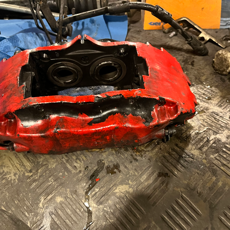 Beschädigtes rotes Bremssattel-Bauteil vor der Instandsetzung